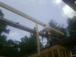 Carpenter setting a ridge beam over a new addition frame — Ice Dam Removal by Roofing Brothers in Dola