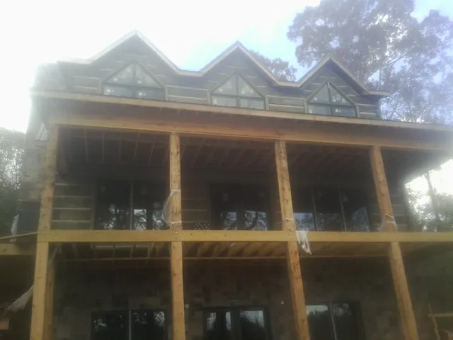 Dormers and porch framing on a large log home under construction — Roof Coating work by our crew in Dola