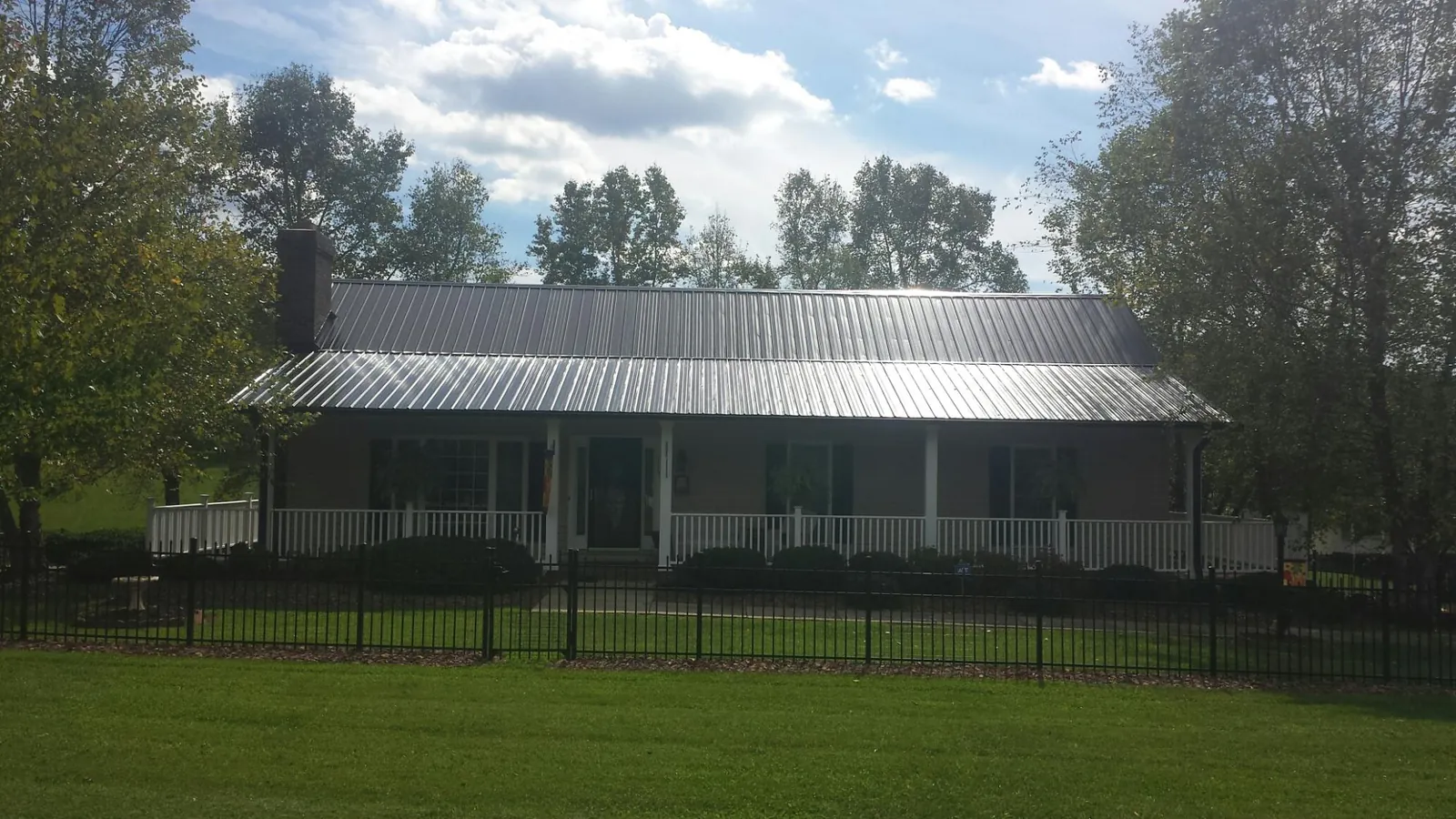 Gray metal roof on a brick ranch with a full width front porch — Gutter Guard Installation work by our crew in Dola