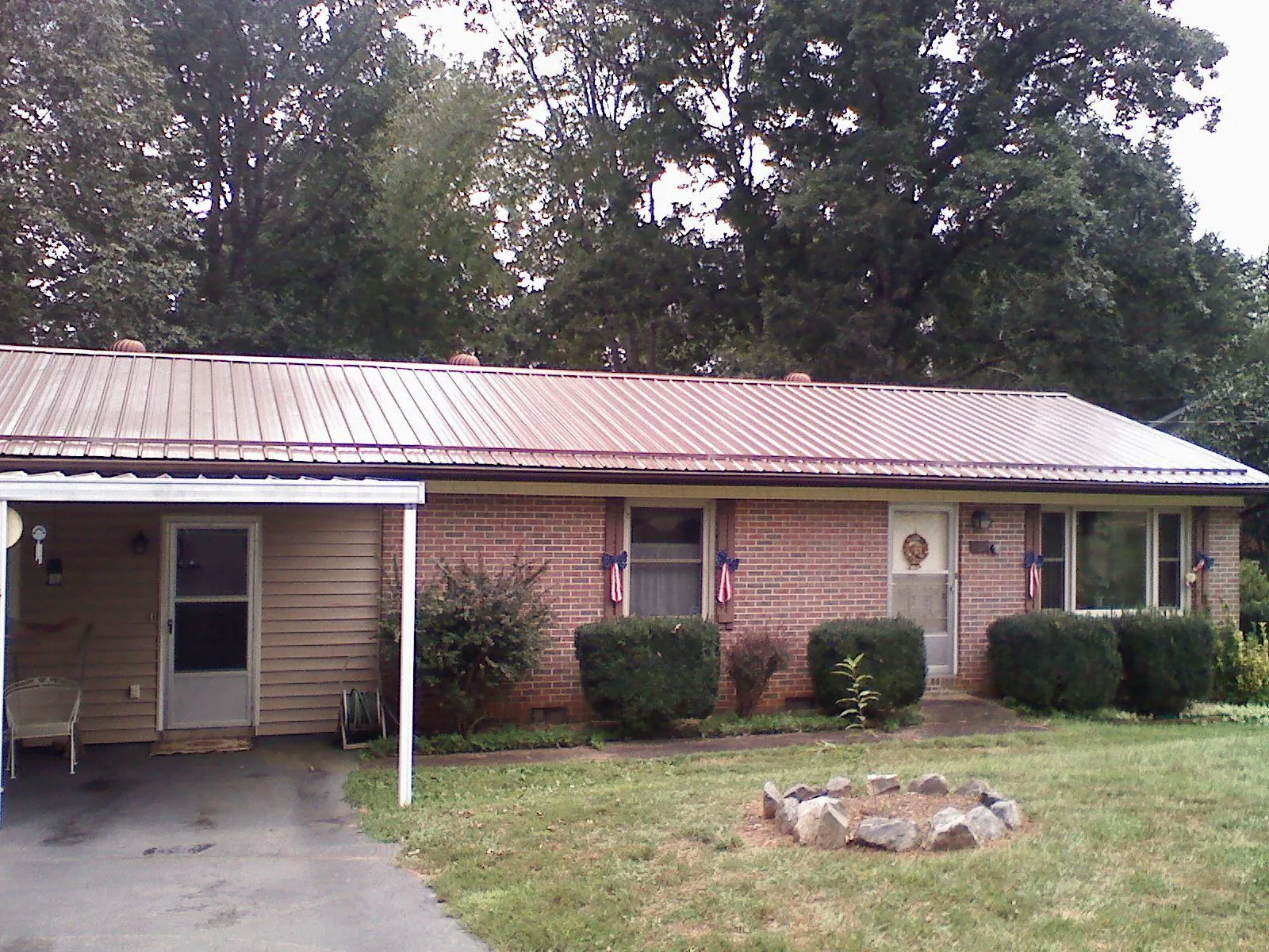 Bronze metal roof and carport on a brick ranch home — Roof Repair work by our crew in Dola